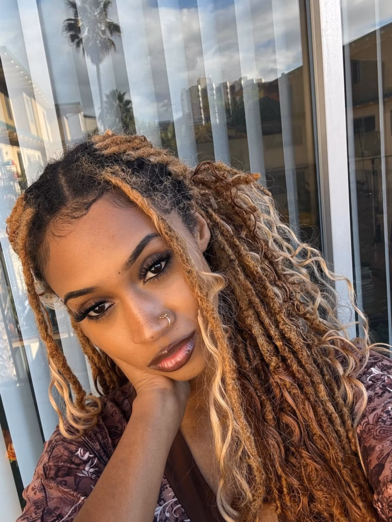 Honey Blonde Locs With Curly Ends Swept to One Side